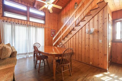 Dining room featuring a wealth of natural light, wood walls, beamed ceiling, and wood-type flooring