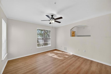 A modern ceiling fan adds both comfort and style to the living room, while the arched pass-through detail provides a subtle architectural touch and connects the space visually to the adjacent area, enhancing flow and functionality.