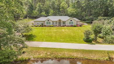 Ranch-style house featuring a front yard, a porch, a water view, and a wooded view
