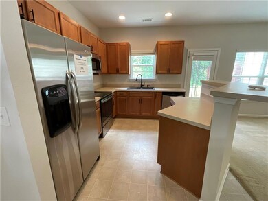 Kitchen featuring stainless steel appliances, a sink, light countertops, brown cabinets, and recessed lighting
