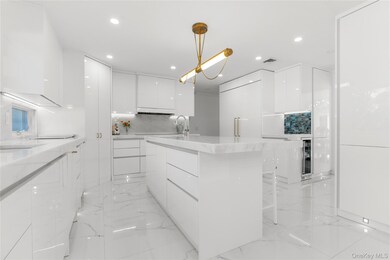 Kitchen with modern cabinets, white cabinetry, light marble finish flooring, light stone counters, and recessed lighting