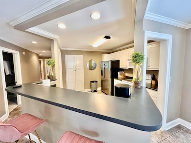Kitchen featuring white stove, dark countertops, crown molding, a peninsula, and a breakfast bar