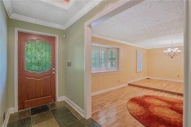 Foyer entrance with a textured ceiling, a chandelier, baseboards, crown molding, and dark wood-type flooring