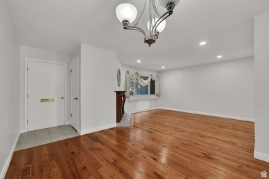 Unfurnished room with light wood-type flooring, a chandelier, and recessed lighting
