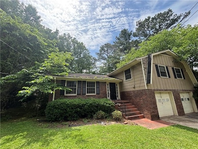 Tri-level home featuring brick siding, a garage, a front lawn, and driveway