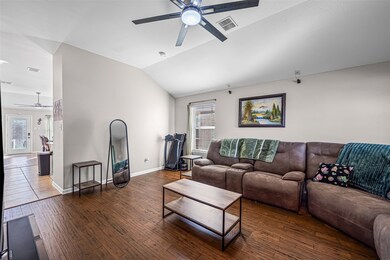 Living room featuring ceiling fan, lofted ceiling, and dark wood-type flooring