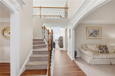 Staircase featuring arched walkways, a towering ceiling, crown molding, and wood finished floors
