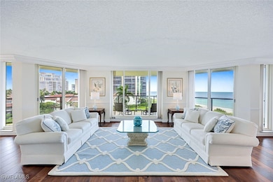 Living area featuring dark wood-style flooring, a textured ceiling, expansive windows, and a water view