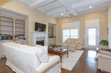 Living area featuring a high end fireplace, a ceiling fan, dark wood-style flooring, ornamental molding, and beamed ceiling