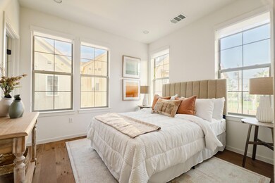 Bedroom with wood finished floors and multiple windows