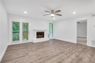 Unfurnished living room featuring ceiling fan, light wood-style flooring, baseboards, a fireplace, and recessed lighting