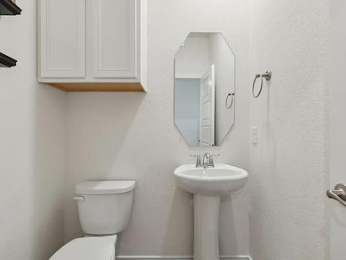 Bathroom with a textured wall, toilet, and a sink