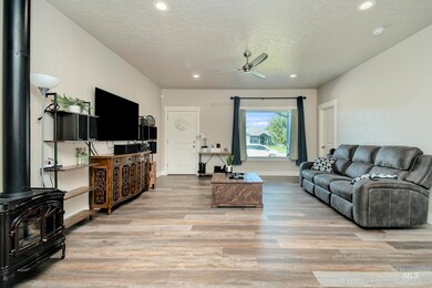 Living room with a ceiling fan, light wood-style flooring, recessed lighting, a textured ceiling, and a wood stove