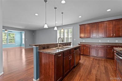 Kitchen with dark countertops, dark wood finished floors, healthy amount of natural light, stainless steel dishwasher, and recessed lighting