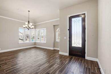 Foyer featuring wood tiled floors, a chandelier, and crown molding