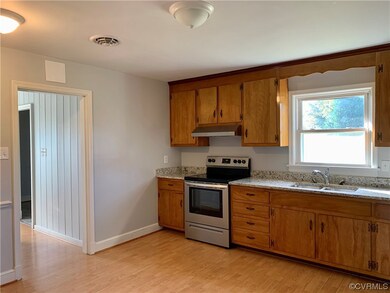 Kitchen featuring stainless steel electric stove, light wood-type flooring, light stone countertops, and sink