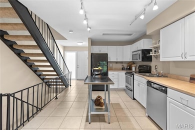 Kitchen with light countertops, open shelves, appliances with stainless steel finishes, white cabinets, and light tile patterned floors