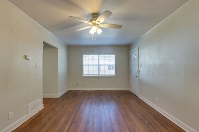 Room with a textured wall, dark wood-type flooring, crown molding, ceiling fan, and a textured ceiling