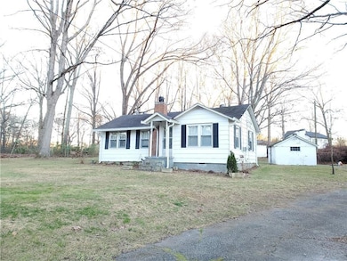 Ranch-style home with a chimney, a front lawn, crawl space, and an outbuilding
