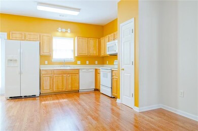 Kitchen with light countertops, light wood-type flooring, a sink, and white appliances