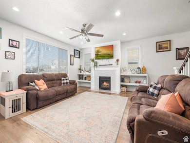Living room featuring a textured ceiling, a wealth of natural light, light flooring / wood-style floors, and ceiling fan