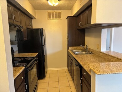 Kitchen with black appliances, sink, a textured ce