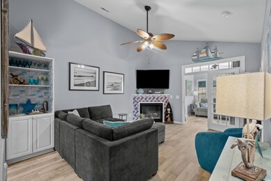 Living area featuring light wood finished floors, fireplace and vaulted ceiling.