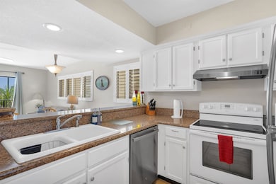 Kitchen featuring white cabinetry, white range with electric stovetop, dishwasher, under cabinet range hood, and a textured ceiling