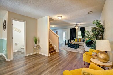 Living room with stairway, a textured ceiling, wood finished floors, and ceiling fan