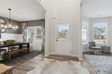 Foyer entrance featuring a chandelier, plenty of natural light, and wood finished floors