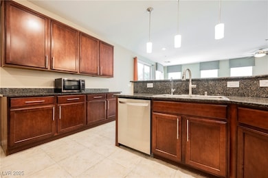 Kitchen with stainless steel appliances, pendant lighting, dark stone countertops, and ceiling fan