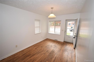 Unfurnished dining area with hardwood / wood-style floors and a textured ceiling