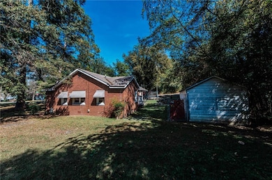View of side of home with a gate, brick siding, and a storage unit