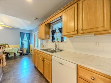 Kitchen featuring dishwasher, dark floors, decorative backsplash, and plenty of natural light
