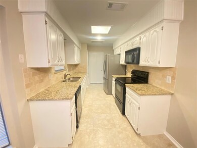 Kitchen with black appliances, light granite stone