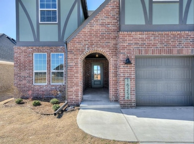 Property entrance featuring brick siding, driveway, and a garage