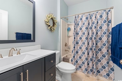 Full bath with vanity, shower / bathtub combination with curtain, toilet, and tile patterned floors