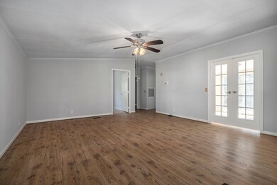 Fantastic, large living space featuring the gleaming flooring, great French doors to open up the space, ceiling fan and the crown moldings.