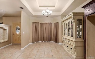 Foyer entrance featuring a chandelier, light tile patterned floors, and a tray ceiling