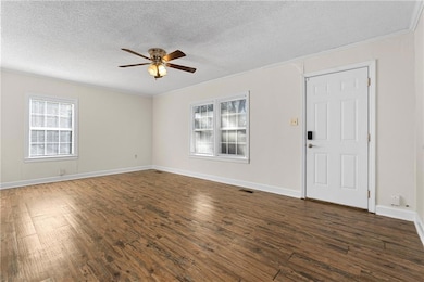 Spare room featuring ornamental molding, dark wood-style floors, a textured ceiling, and a ceiling fan
