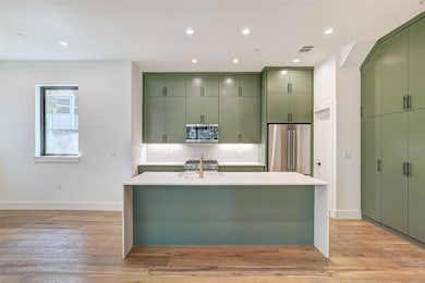 Kitchen with green cabinetry, stainless steel app