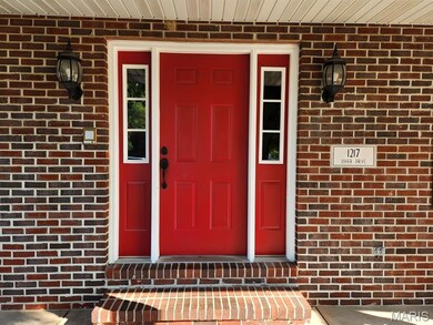 View of exterior entry featuring brick siding and a porch