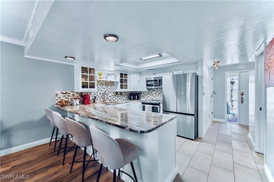 Kitchen featuring a peninsula, white cabinets, a k