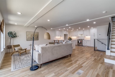 Living room featuring light wood-style flooring, recessed lighting, stairs, and beamed ceiling