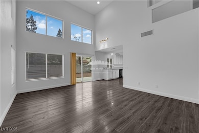 Unfurnished living room featuring dark wood finished floors and a high ceiling