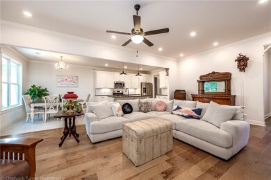 Open living area is filled with an abundance of natural light & handsome wood flooring