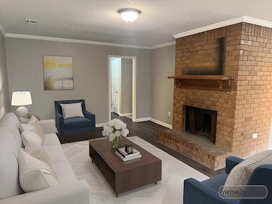 Living room featuring wood finished floors, a fireplace, crown molding, and a textured ceiling