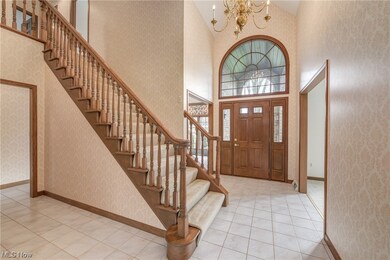 Entrance foyer with high vaulted ceiling, light tile floors, and a chandelier