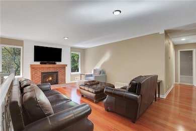 Living area featuring light wood-type flooring, a brick fireplace, ornamental molding, and recessed lighting