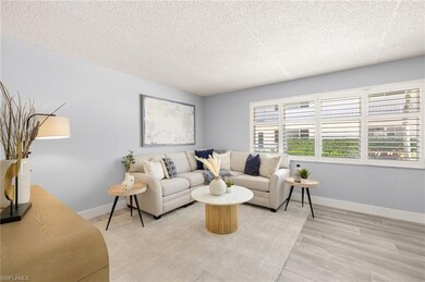 Living area featuring a textured ceiling, light wood-style floors, and baseboards
